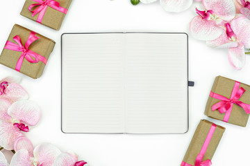 flatlay of Gift present boxes with pink ribbon and orchid flowers .Note book. spring concept. Copy space