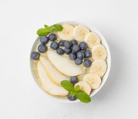 Healthy fruit Breakfast: smoothie in a bowl with banana, pear, kiwi, blueberries, lime and mint. Vegan food