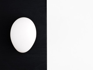Fototapeta na wymiar White egg on a black wooden and white background. Healthy eating concept