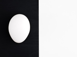 White egg on a black wooden and white background. Healthy eating concept