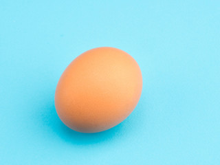 One brown chicken egg on a blue background. Healthy eating concept