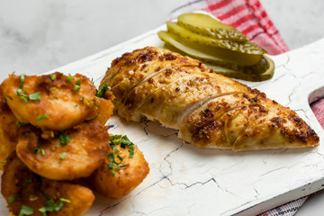 Baked whole chicken with potatoes and herbs in a rustic style. Top view, side view on a light background. Close-up and medium plan. Space for text.