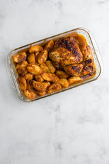 Baked whole chicken with potatoes and herbs in a rustic style. Top view, side view on a light background. Close-up and medium plan. Space for text.