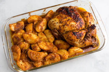 Baked whole chicken with potatoes and herbs in a rustic style. Top view, side view on a light background. Close-up and medium plan. Space for text.