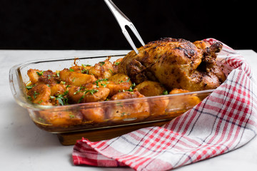 Baked whole chicken with potatoes and herbs in a rustic style. Top view, side view on a light background. Close-up and medium plan. Space for text.