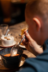 man tastes soup with a spoon.A man eats soup. view from the back