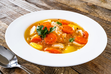 Bowl of hot cabbage soup on wooden table