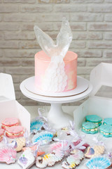 Mermaid theme candy bar with cake, cupcakes, macaroons and biscuits. Sea shell shaped macaroons with pearls.