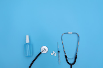 Thermometer, sanitizer, ampoule stethoscope and blister packed medicines over blue backdrop. Concept of healthcare, online shopping, high cost of medicines. expensive medicine. selective focus