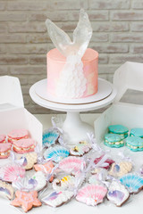Mermaid theme candy bar with cake, cupcakes, macaroons and biscuits. Sea shell shaped macaroons with pearls.