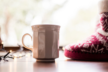 cup of coffee and winter boots on a table with background lights