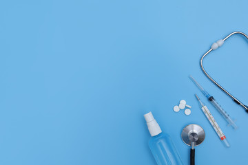 Thermometer, sanitizer, ampoule stethoscope and blister packed medicines over blue backdrop. Concept of healthcare, online shopping, high cost of medicines. expensive medicine. selective focus