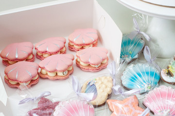 Mermaid theme candy bar with cake, cupcakes, macaroons and biscuits. Sea shell shaped macaroons with pearls.