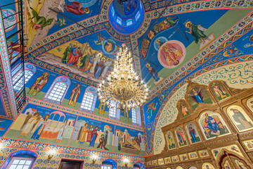 Fototapeta na wymiar Eastern сhristian orthodox сhurch of Byzantine tradition. Traditional religious paintings and colorful traceries on the ceiling. Huge golden chandelier