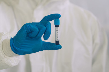 Lab Technician in Personal protective equipment  PPE suit holding testing tube