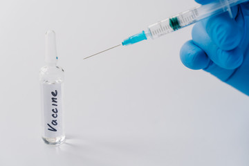 Medical vial and syringe in doctors hand against white background. Vacciantion against infectious...
