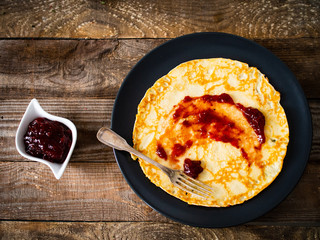 Sweet crepes with fruit jam on wooden table 