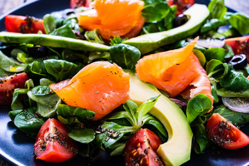 Salmon salad - smoked salmon and vegetables on wooden background

