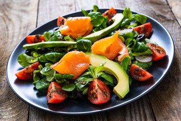Salmon salad - smoked salmon and vegetables on wooden background
