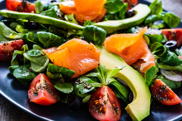 Salmon salad - smoked salmon and vegetables on wooden background
