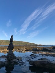 Cairn en équilibre près d'une piscine naturelle chauffée (hot pot) en bord de mer, région des fjords du Nord-Ouest,  Islande