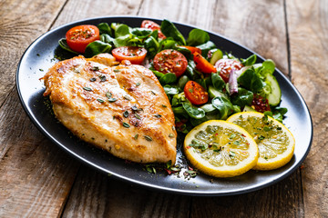 Pork chop with lemon and vegetable salad on wooden background
