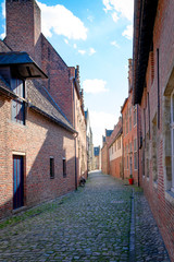 Empty cobblestone streets with red brick buildings from the Great Beguine of Leuven, Belgium, on a sunny day. Travel concept.