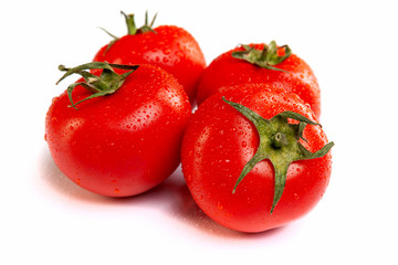 Several ripe juicy red tomatoes in droplets of water, on a white background.