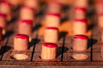 Closeup shot shows space between two wooden red pegs representing social distancing during COVID-19 or Coronavirus pandemic. The wooden peg solitaire is played when people get bored during quarantine.