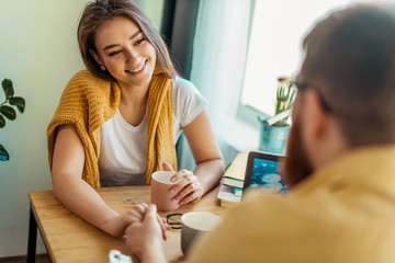 beautiful caucasian married couple drinking tea at home, happy man and woman sit at table have conversation and talk. family indoors