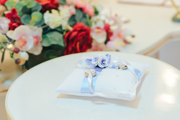 golden wedding rings on small white leather cushion