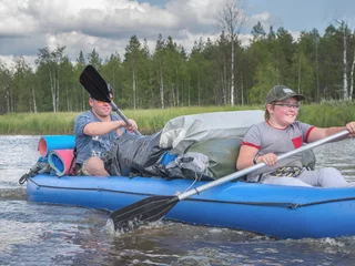 Foto op Canvas Karelia, Vodlozero - 29.07.2019: Tourists, father and son in boat. Ecotourism, visiting fragile, undisturbed natural areas. Active holidays in Karelia. Water rafting in North lakes and rivers © Natalia