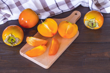 ripe persimmon on a wooden background close-up. a whole persimmon and half a persimmon on the table.