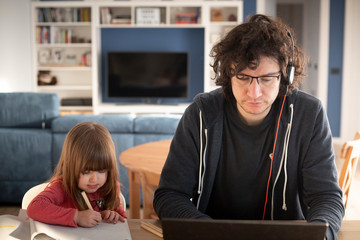 Young father working from home with little daughter drawing during covid-19 lockdown. Child drawing...
