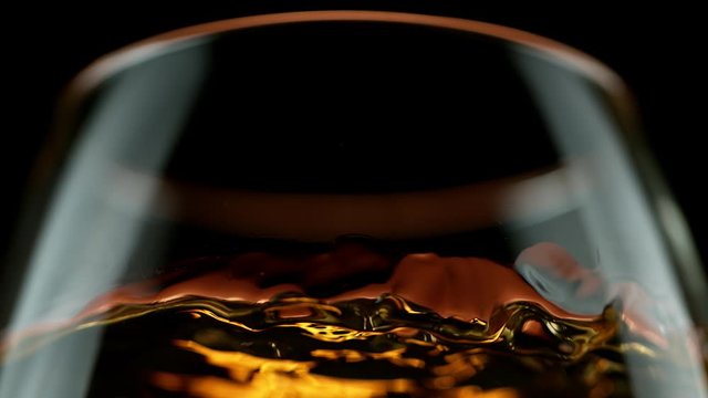 Super slow motion of waving whiskey, cognac or rum in macro shot. Filmed on high speed cinema camera, 1000 fps