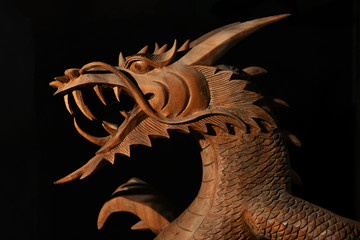 brown wooden oriental dragon with open mouth on a black background