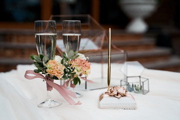Wedding glasses with champagne on a white tablecloth outdoors.