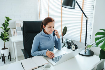 Asian woman working from home using computer and drinking coffee in her bedroom document finance and conference online meeting for new projects