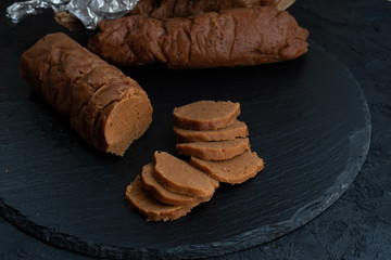 Cooked seitan sausages on slate board