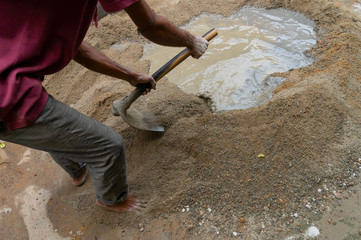Indian labour mixing cement using shovel.