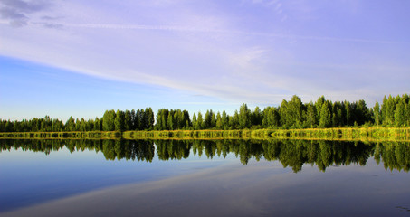 Fototapeta na wymiar landscape. the sky and the green forest are reflected in the surface of the lake. horizontal photo