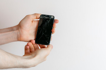 person's hands holding a crashed broken phone, mobile smartphone