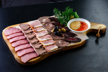 Set mix jerky, sausage, salami and bacon served on a wooden board