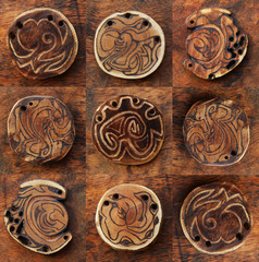 Collage of nine handmade wooden pendants on plywood background. 