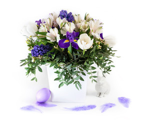 Easter decorations. Spring flowers with an Easter egg and a rabbit on a white background. Copy space.