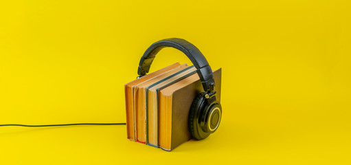 listen to the audio books concept, big headphones put on the stack of books isolated, simple style