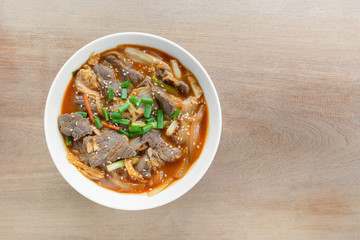 top view of stir fried beef with kimchi in a ceramic bowl on wooden table. asian homemade style food concept.