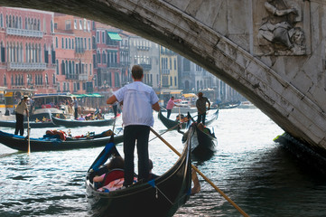 Gondolas with tourists under the Rialto bridge, in the tourist center of the city of Venice Italy. Travel and vacation concept.
