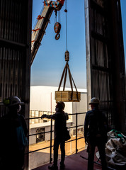 The crane carrying a wooden box of radioactive instrument holder to the high floor of the plant