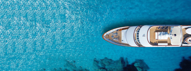 Aerial drone top down ultra wide photo of luxury yacht anchored in tropical exotic island turquoise...